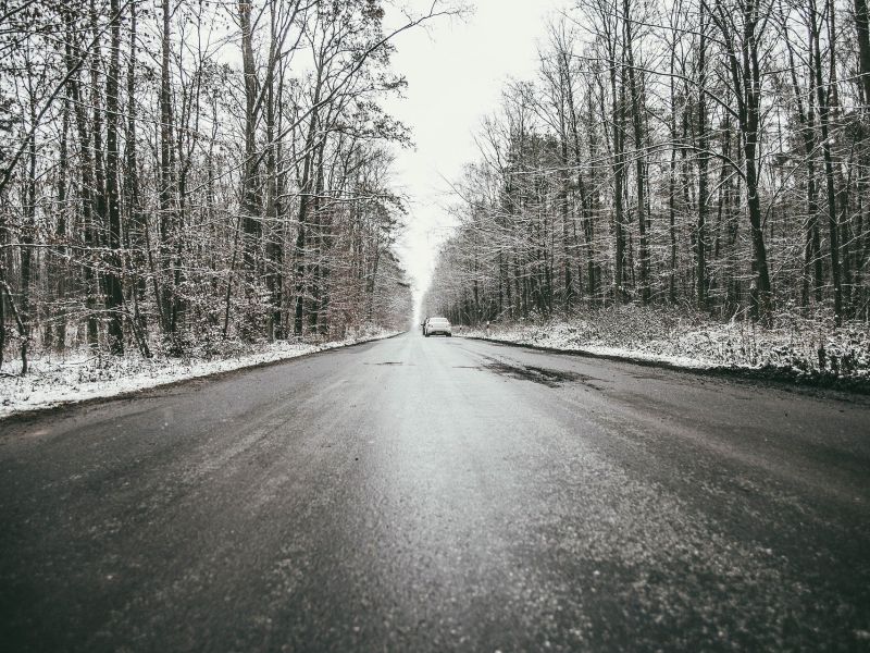 Na zdjęciu ośnieżona droga, obok drzewa pokryte śniegiem