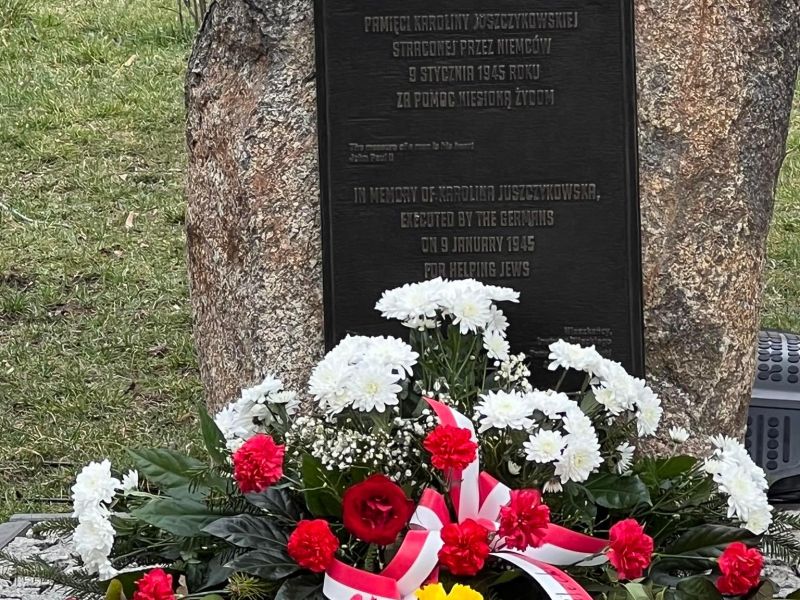Na zdjęciu biało-czerwone kwiaty złożóne przed obeliskiem poświęconym Karolinie Juszczykowskiej, tomaszowiance zamordowanej przez Niemców za pomoc Żydom