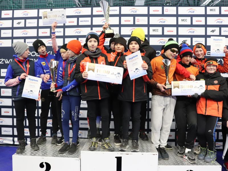 Na zdjęciu grupa młodych łyżwiarzy z pucharami i dyplomami, zdjęcie grupowe na podium. Zdjęcie wykonane po zawodach OZD i Mistrzostwach Tomaszowa Mazowieckiego w łyżwiarstwie szybkim