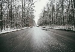 Na zdjęciu śliska droga w lesie pokryta warstwą lodu